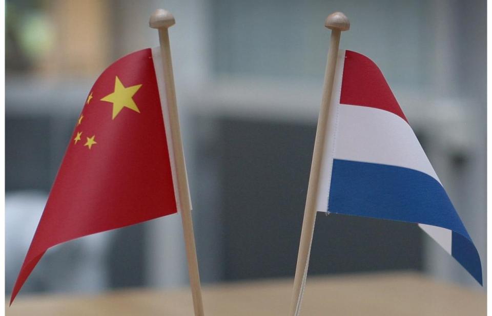 Kleine vlaggen van China en Nederland, rechtop en schuin van elkaar weg. 