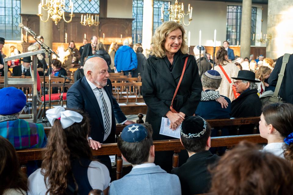 Kamervoorzitter Vera Bergkamp staat tussen de synagogegangers in de bankjes en maakt een praatje met hen.