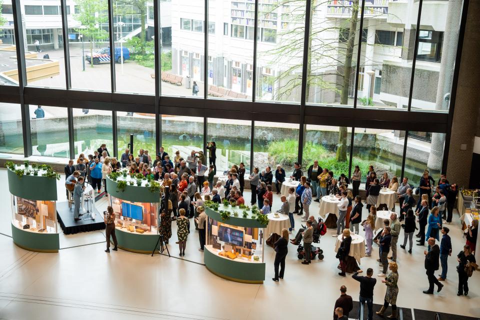 Overzicht van de expositie van bovenaf: de in de Statenpassage geplaatste vitrines zijn zichtbaar, daar omheen bezoekers.