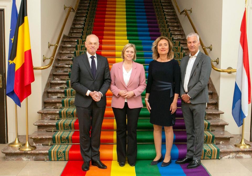 Drie parlementsvoorzitters en een ondervoorzitter staan naast elkaar voor een trap met aan hun zijde vlaggen van de EU, Nederland en België.