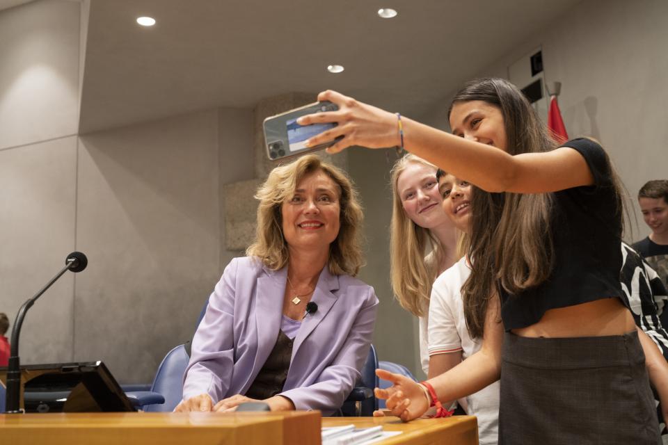 Drie jongeren staan naast Kamervoorzitter Vera Bergkamp en maken een foto.