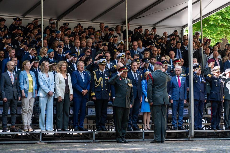 Koning Willem-Alexander neemt het defilé af tijdens Veteranendag. Voor hem staat een veteraan, achter hem een tribune vol met genodigden waaronder Kamervoorzitter Vera Bergkamp.