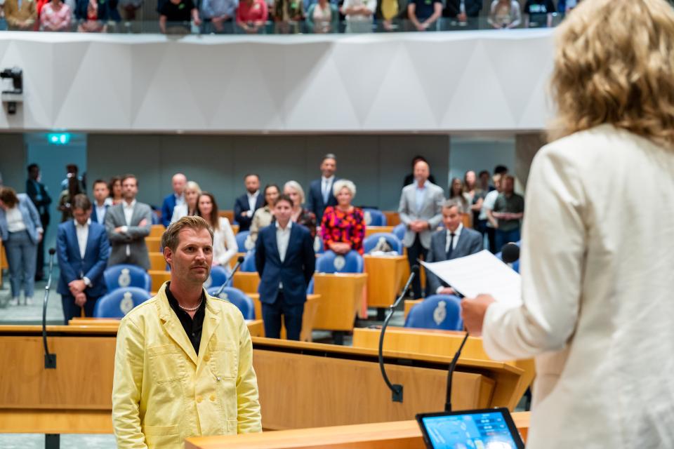 Voorzitter Sjoerd Warmerdam staat tegenover de Voorzitter en zij spreekt hem toe in de plenaire zaal. Kamerleden zijn opgestaan voor dit moment.