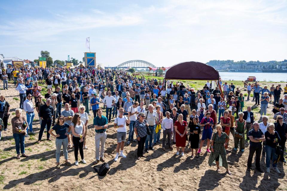 Een grote groep mensen aan de oever van de Waal, van bovenaf gefotografeerd, tijdens het Festival van de Democratie 2019. 