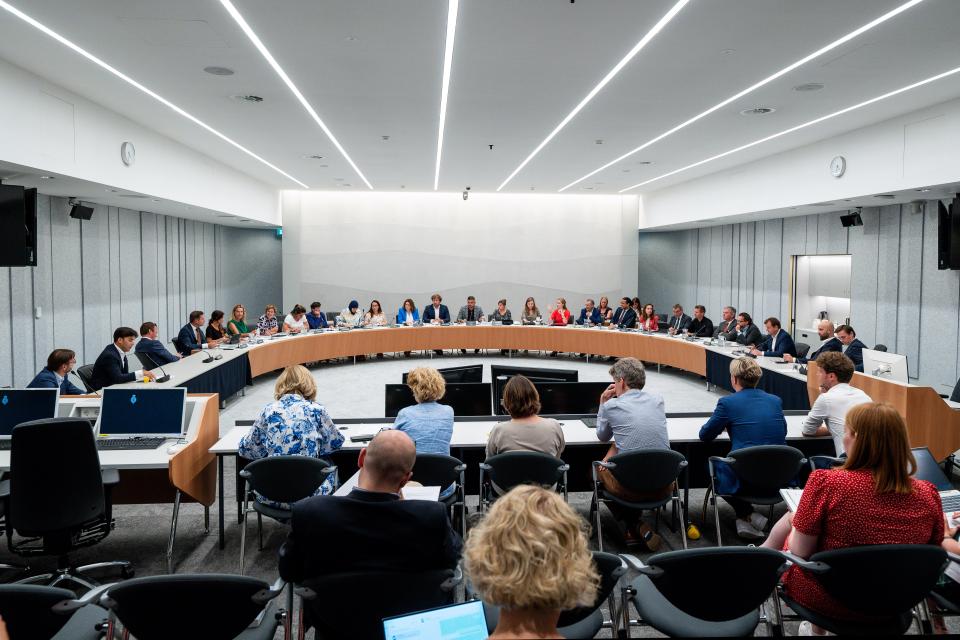 Grote vergaderzaal met tientallen commissieleden