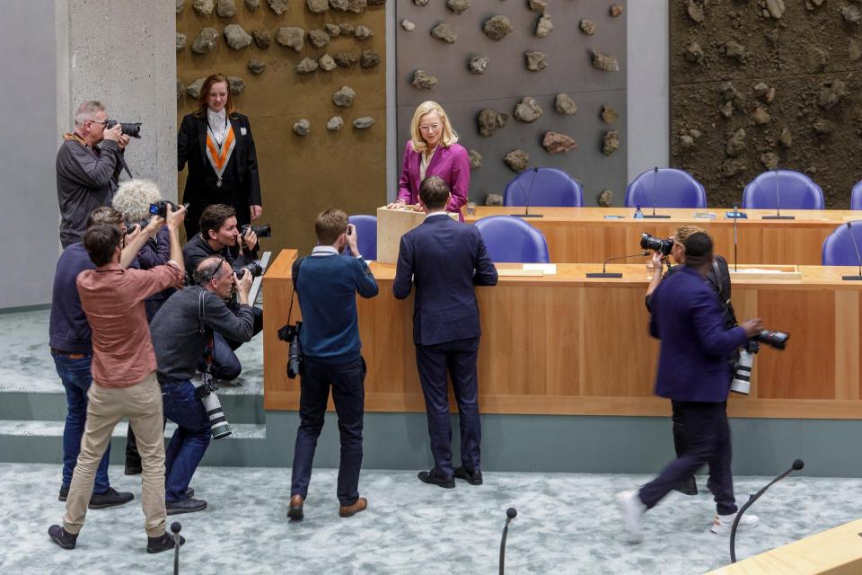 Minister Kaag van Financiën houdt koffertje vast in plenaire zaal, voor haar staan enkele fotografen.