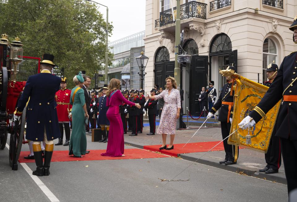 Kamervoorzitter Vera Bergkamp met haar rug naar de ingang van de schouwburg, steekt haar hand uit naar prinses Alexia die over de rode loper nadert. 