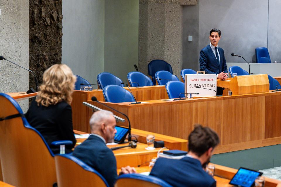 Demissionair minister Rob Jetten in vak K van de plenaire zaal met een koffer waar 'handle with care Klimaatdag' op staat.