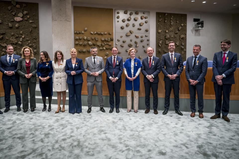 Voorzitter Vera Bergkamp poseert in de plenaire zaal met 11 Kamerleden die van haar een koninklijke onderscheiding opgespeld kregen. 