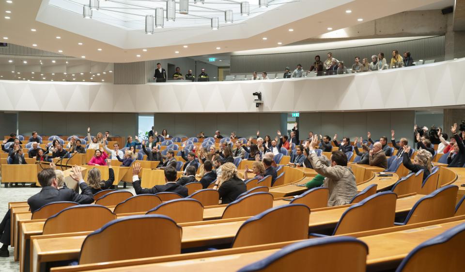 Plenaire zaal van de Tweede Kamer. Kamerleden steken hand omhoog tijdens stemming.