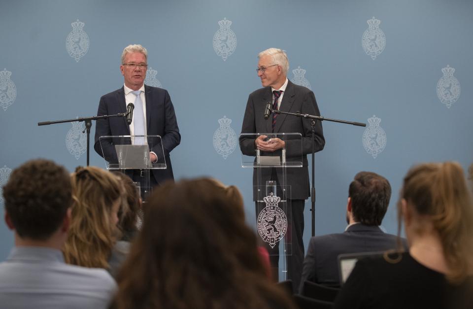 Informateurs Elbert Dijkgraaf en Richard van Zwol staan beiden voor een katheder met een microfoon. Op de achtergrond een blauw scherm met logo’s van de Tweede Kamer.  Op de voorgrond achterhoofden van mensen die zitten te kijken naar het persmoment.