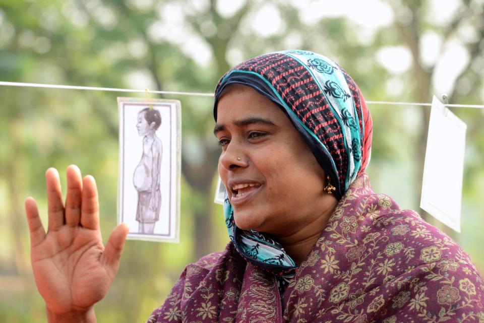 Een vrouw aan het woord, naast haar hangt een afbeelding van een zwangere vrouw aan een waslijn.  