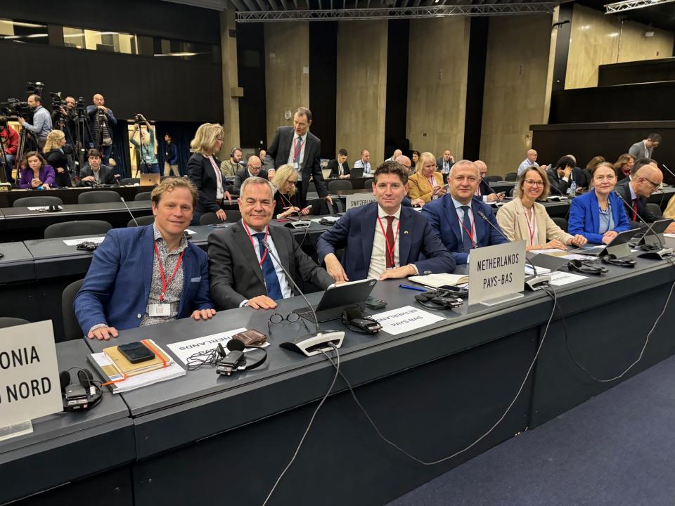 op de foto in de plenaire vergaderzaal in Sofia zit de Nederlandse afvaardiging in de bankjes. op de foto staan de Tweede Kamerleden Paternotte, Kahraman en Tuinman en Eerste Kamerlid Petersen.