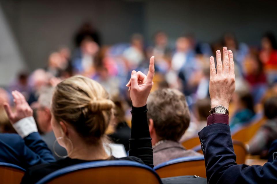 Kamerleden steken hun hand op tijdens een stemming.