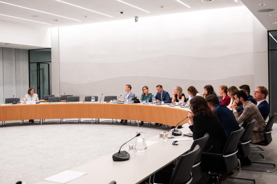De kandidaat-minister links aan een gebogen tafel, rechts op de voorgrond de commissieleden. 