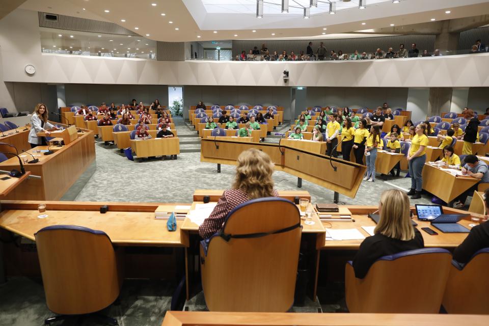 Plenaire vergaderzaal gefotografeerd vanachter de Voorzitter. Jongeren aan de interruptiemicrofoons.