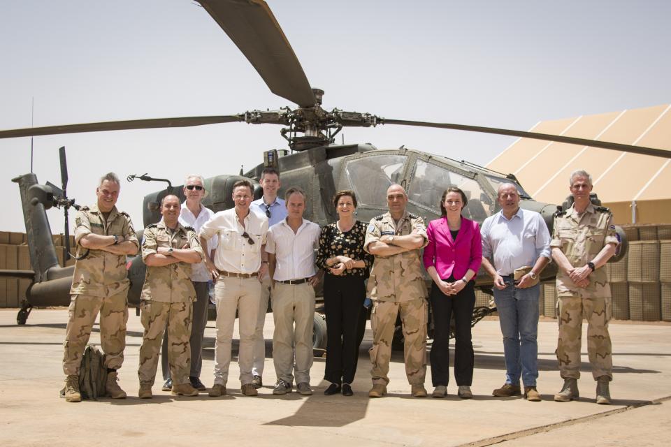 Kamerleden en Nederlandse militairen poseren voor een helikopter