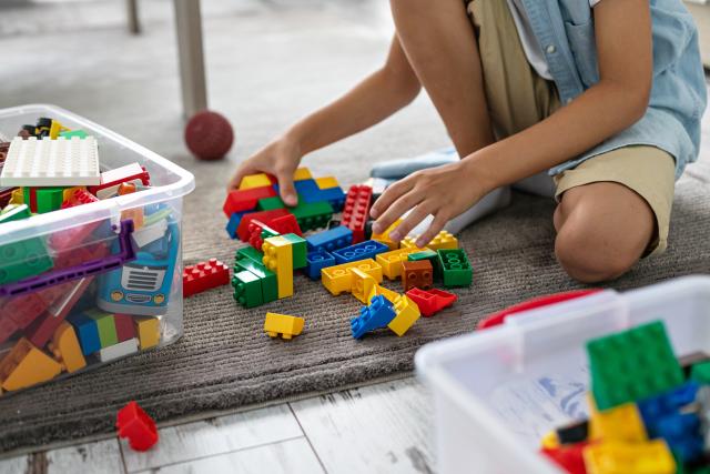 Kind zit op de grond en speelt met duplo