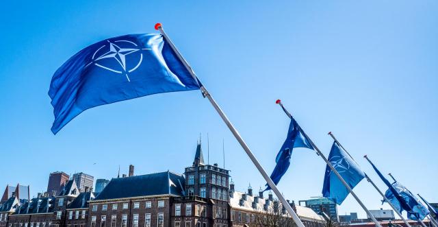 Een rij aan NAVO-vlaggen wappert een de Hofvijver in het centrum van Den Haag 