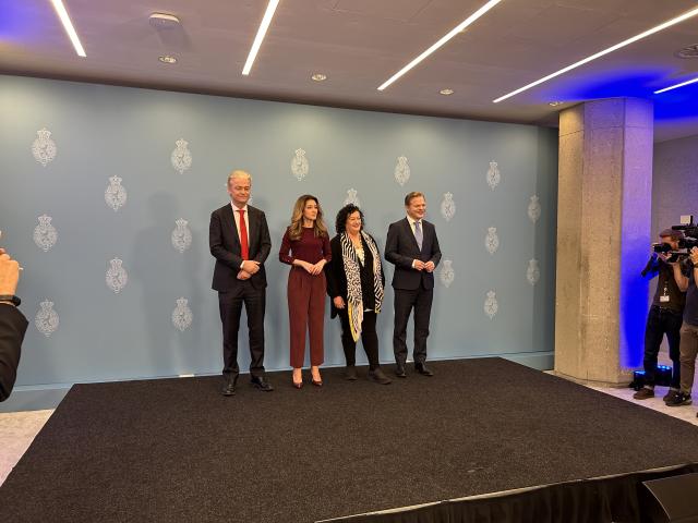 De vier fractievoorzitters poseren staand op een podium voor een griijze wand met daarop meerdere keren het wapen van de Tweede Kamer afgebeeld. Van links naar rechts Geert Wilders (PVV), Dilan Yeşilgöz (VVD), Caroline van der Plas (BBB) en Pieter Omtzigt (NSC). 