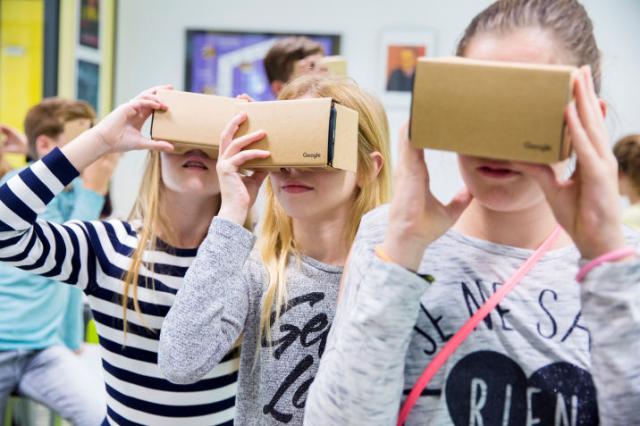 De kinderen kijken in de cardboard van Google. Dat is een soort kartonnen bril waarin een smartphone is bevestigd.