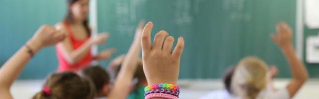 Een basisschoolleerlinge steekt haar hand op in de klas